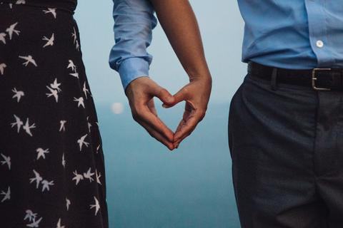 Hands of a man and woman making a heart sign